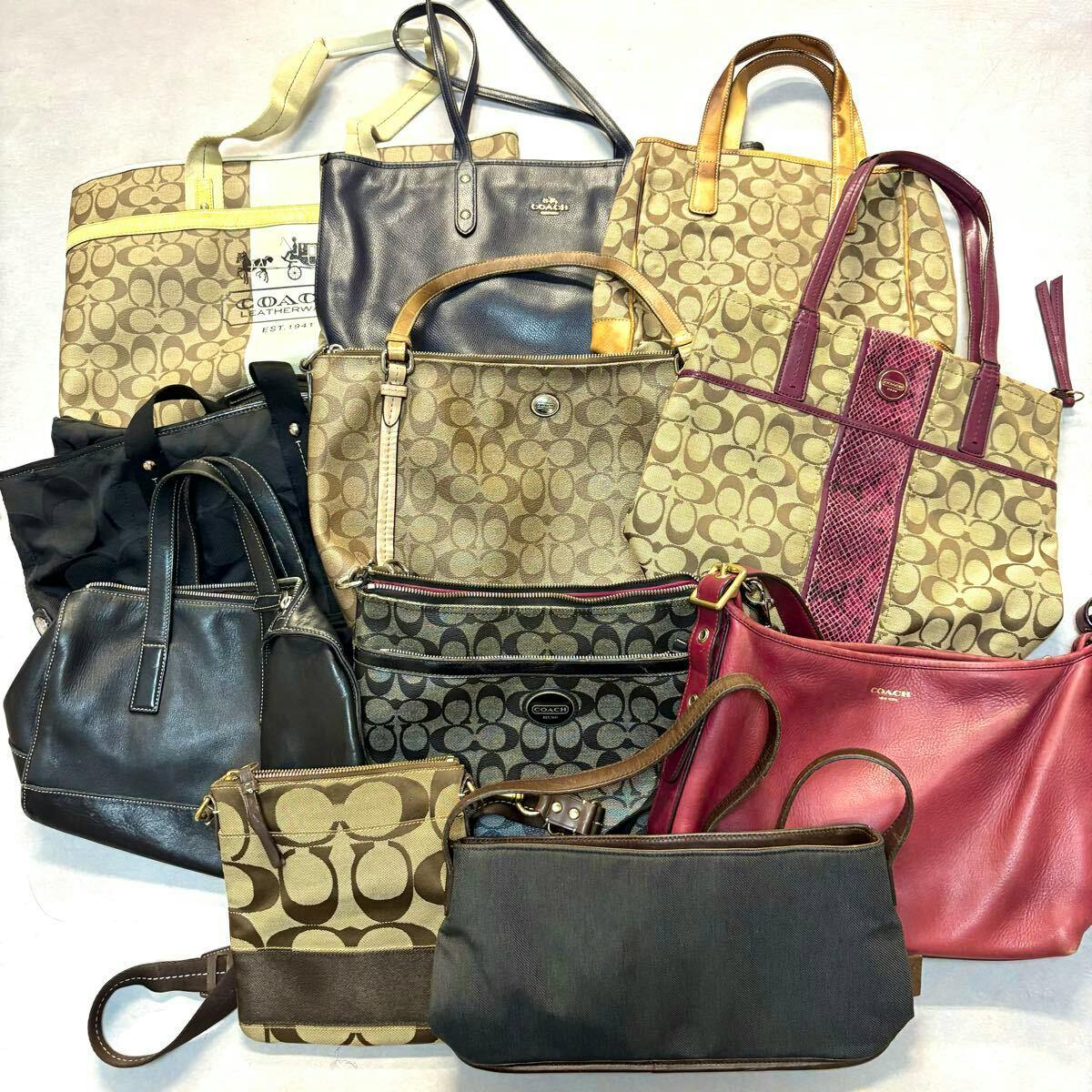 A bulk set of Coach handbags and small bags in signature canvas and leather arranged on a flat surface.
