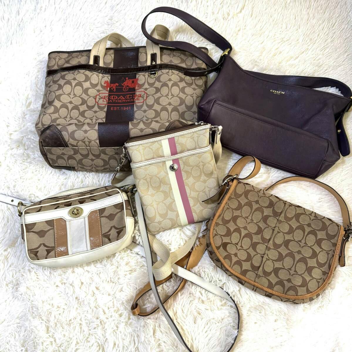 Five COACH bags, including signature monogram tote and several crossbody/shoulder bags, arranged on a white fuzzy background.