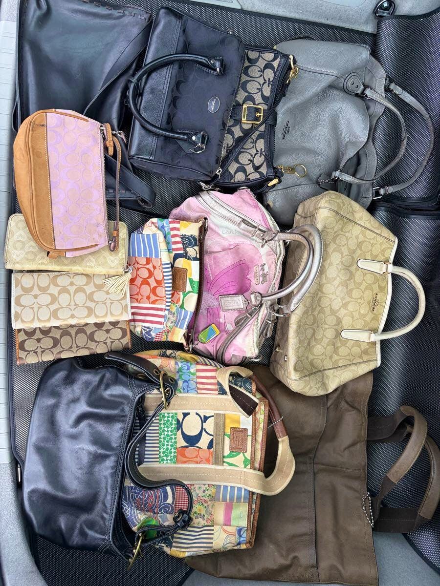 Multiple COACH bags and pouches laid out together showing signature patterns and various styles.