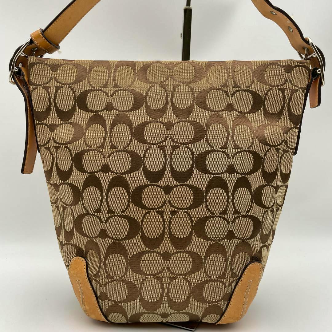 Front view of a beige Coach canvas shoulder bag with signature C pattern and tan leather trim.