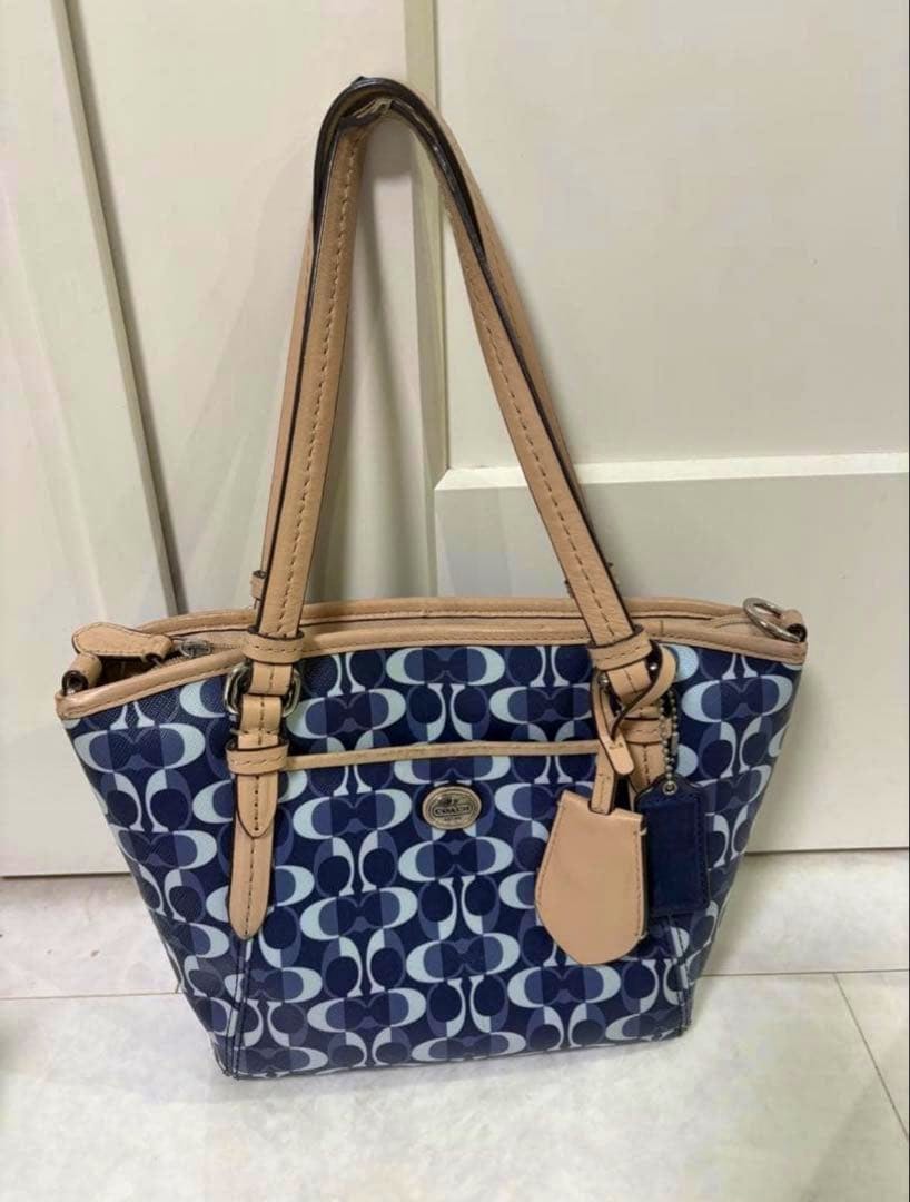 COACH signature navy canvas handbag with tan leather handles and a front logo tag.