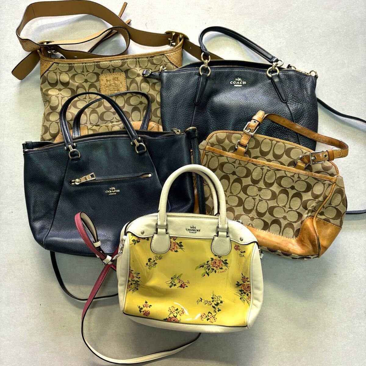 Five COACH handbags and totes arranged on a light surface, including a yellow floral small bag, brown signature 'C' canvas bags, and black leather bags.