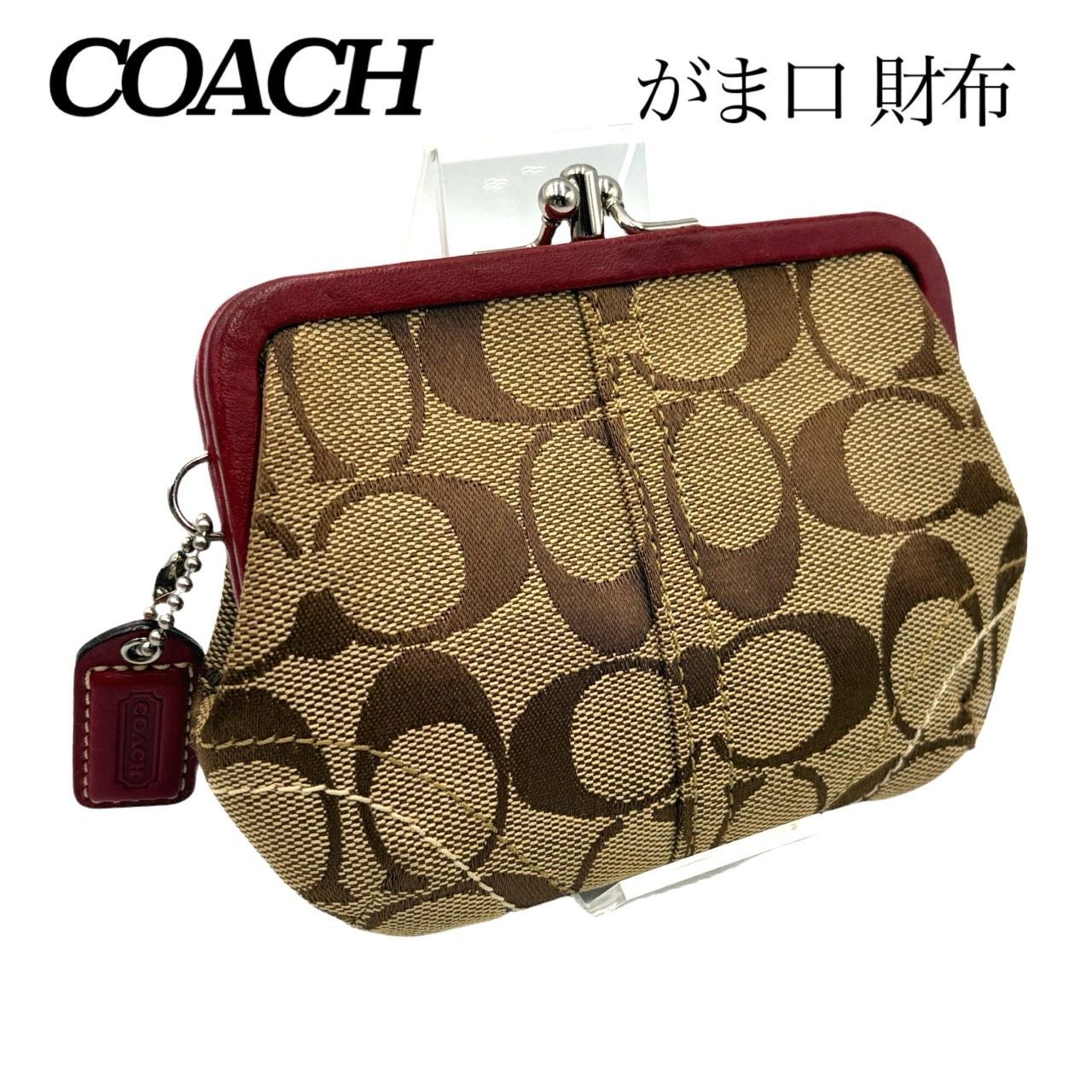 Canvas COACH coin case in beige signature pattern with red trim and a metal kiss‑lock closure.