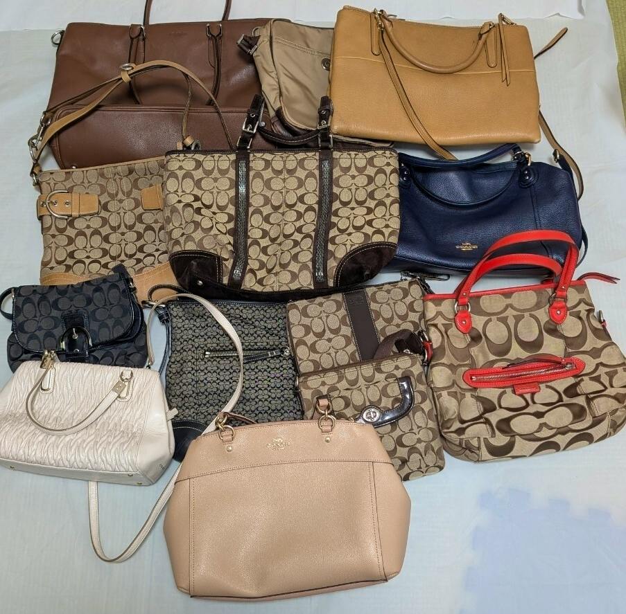 Several Coach handbags and totes laid out on a surface, showing signature C canvas and leather styles.