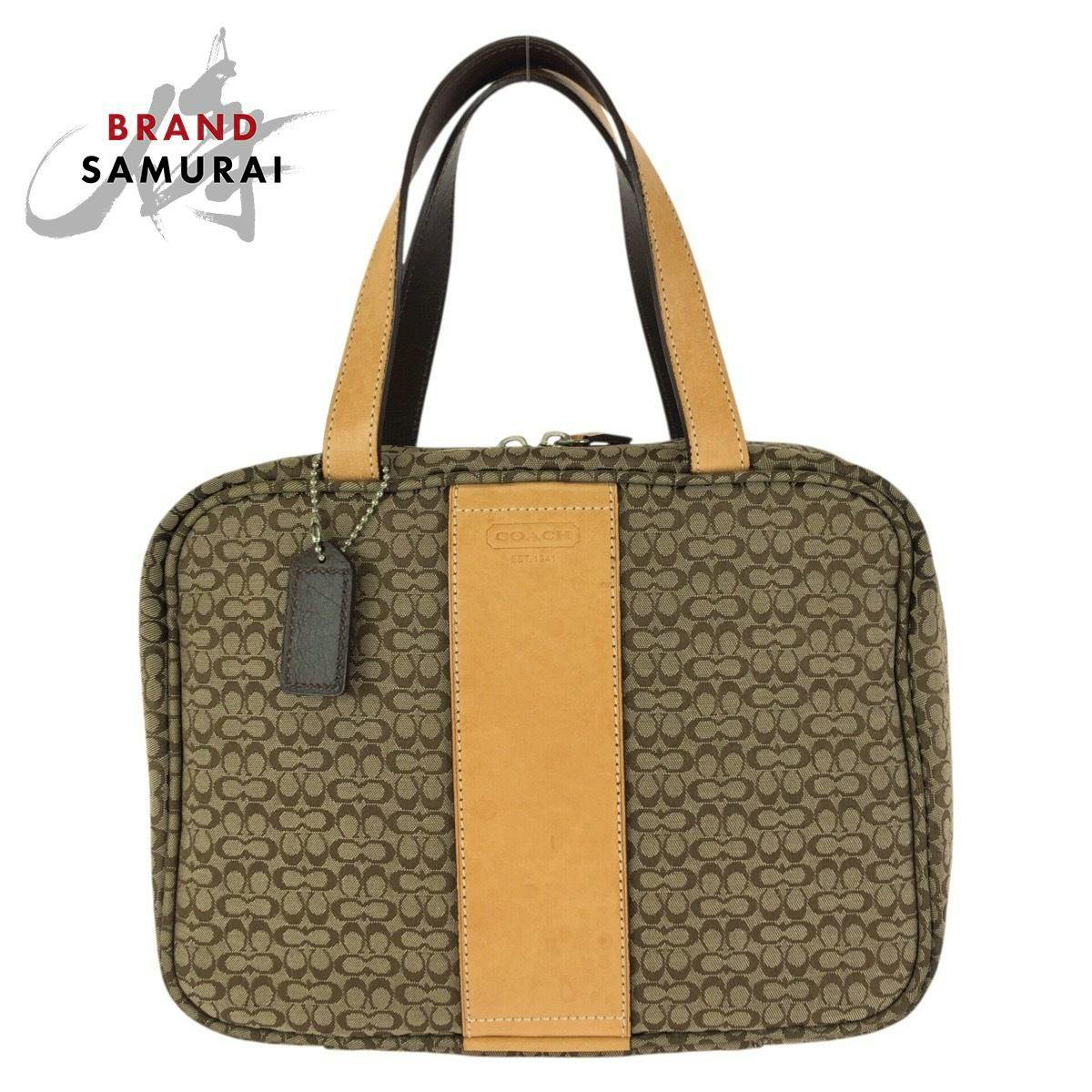 Front view of a Coach brown/beige signature canvas tote with a tan leather center stripe and double top handles.