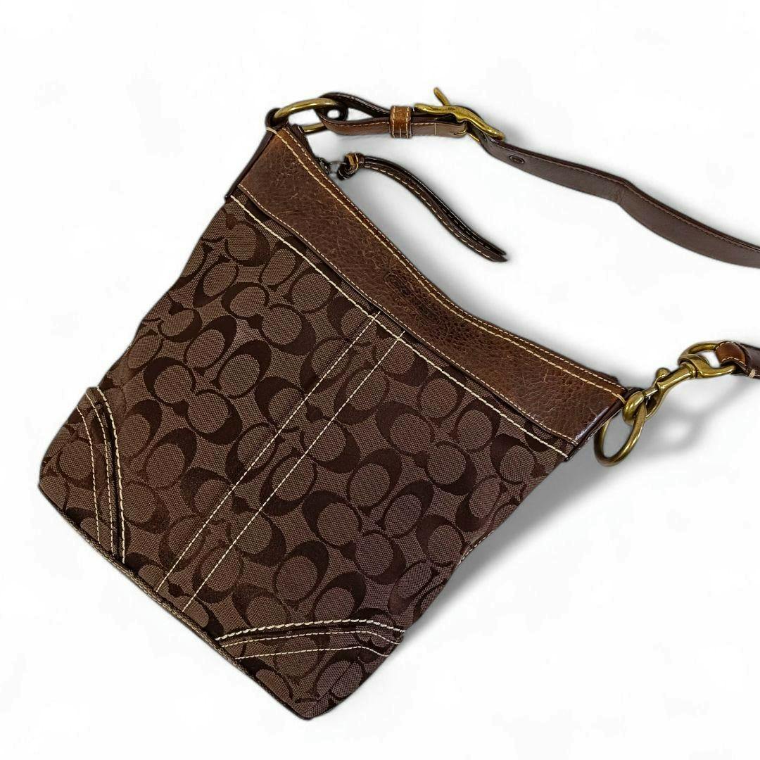 Brown Coach signature canvas shoulder bag with leather trim, brass hardware, and an adjustable strap on a white background.