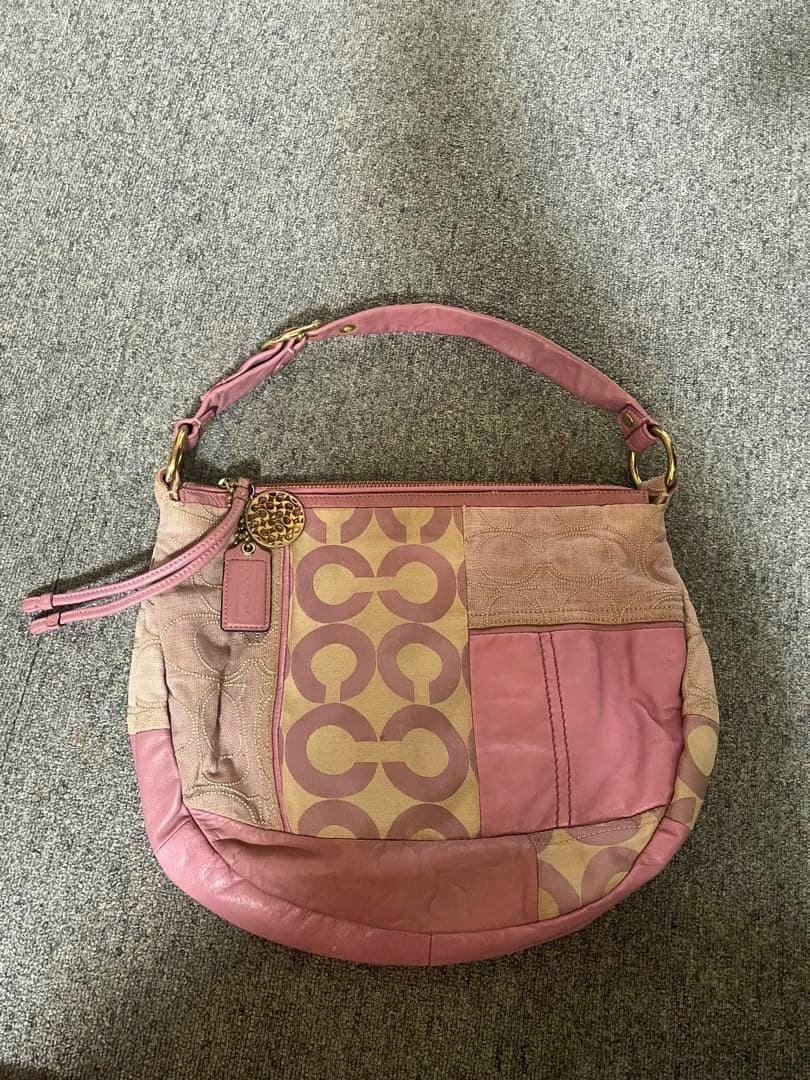 Pink COACH signature canvas shoulder bag shown flat on a grey carpet, front view.