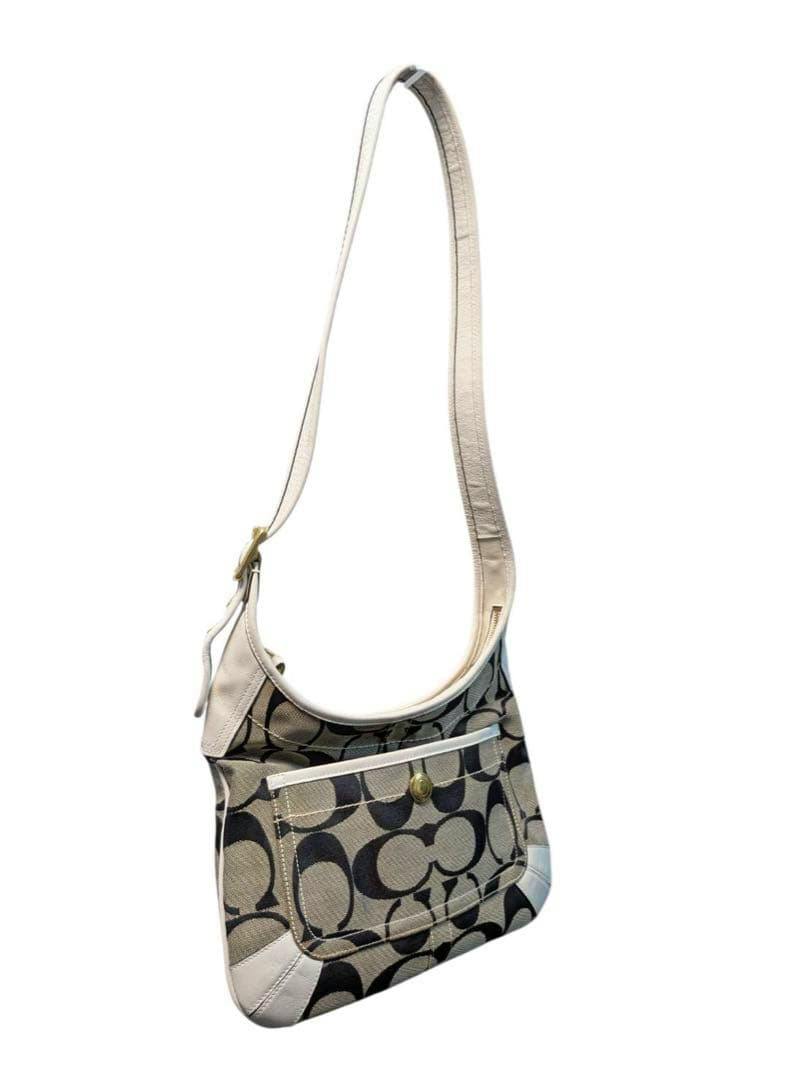 White Coach signature canvas shoulder bag with large C pattern and a front snap pocket.