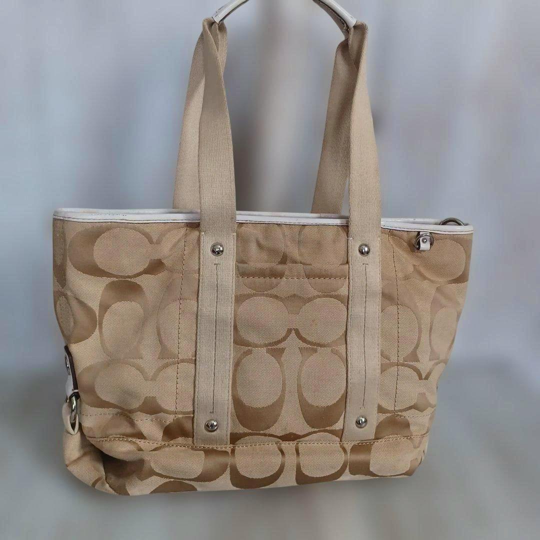 Beige COACH signature canvas tote bag shown front-facing with two shoulder straps.
