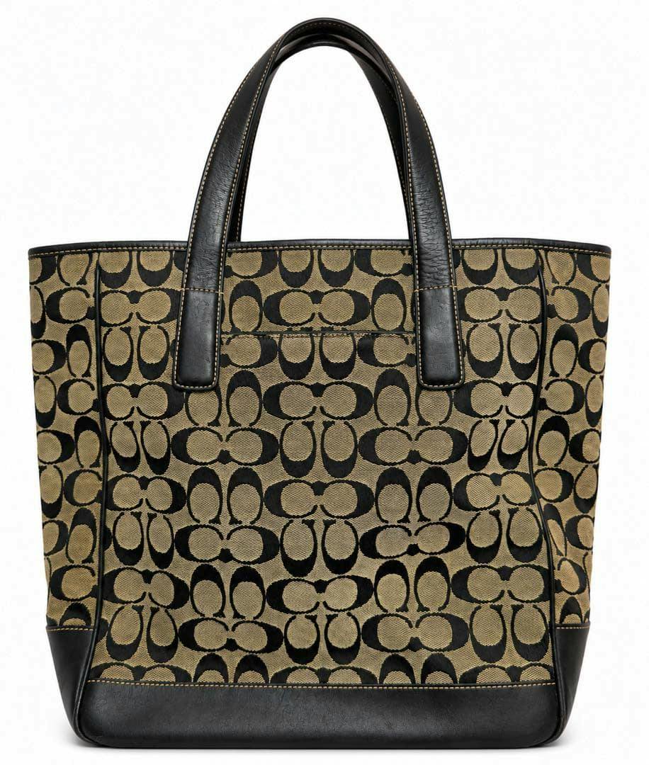 Front view of a COACH signature canvas tote bag with black leather handles and signature pattern.