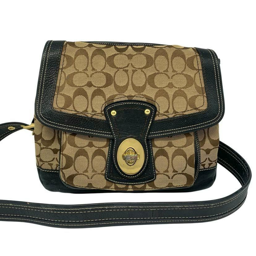 Front view of a Coach signature canvas shoulder bag with brown monogram pattern, black leather trim, turn-lock closure, and shoulder strap.