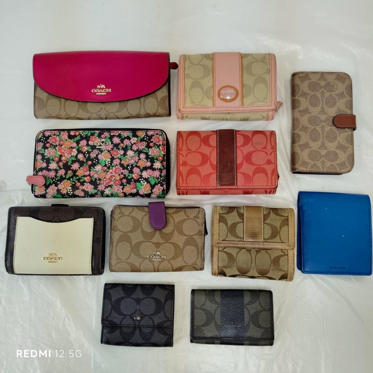 Multiple COACH wallets and small cases in signature canvas and leather arranged on a white surface.