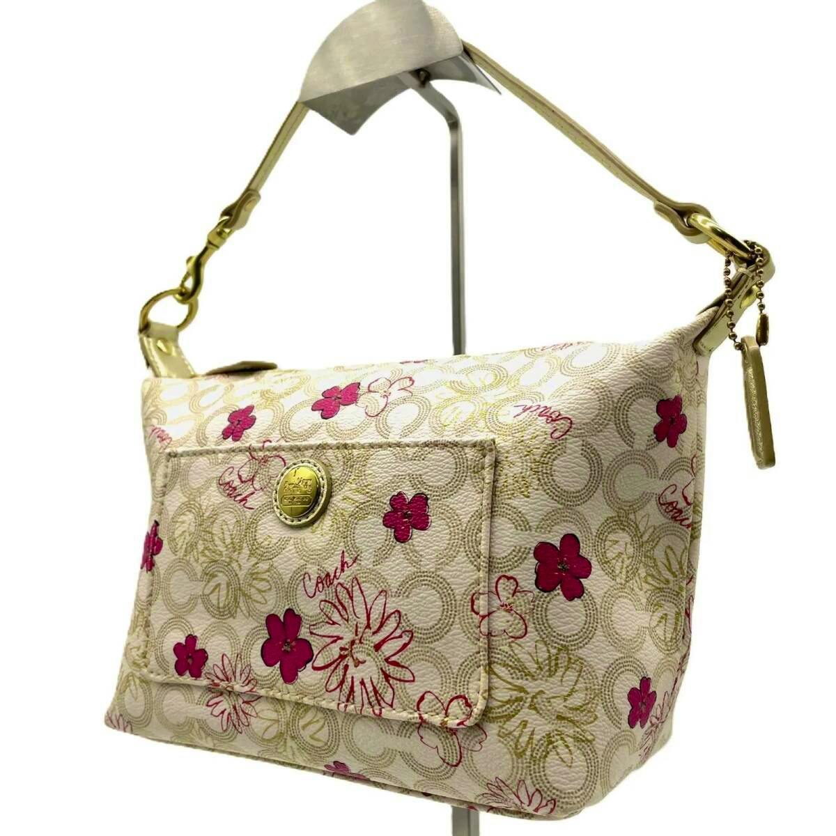 Ivory Coach floral signature PVC one-shoulder handbag displayed on a stand showing the front and strap.