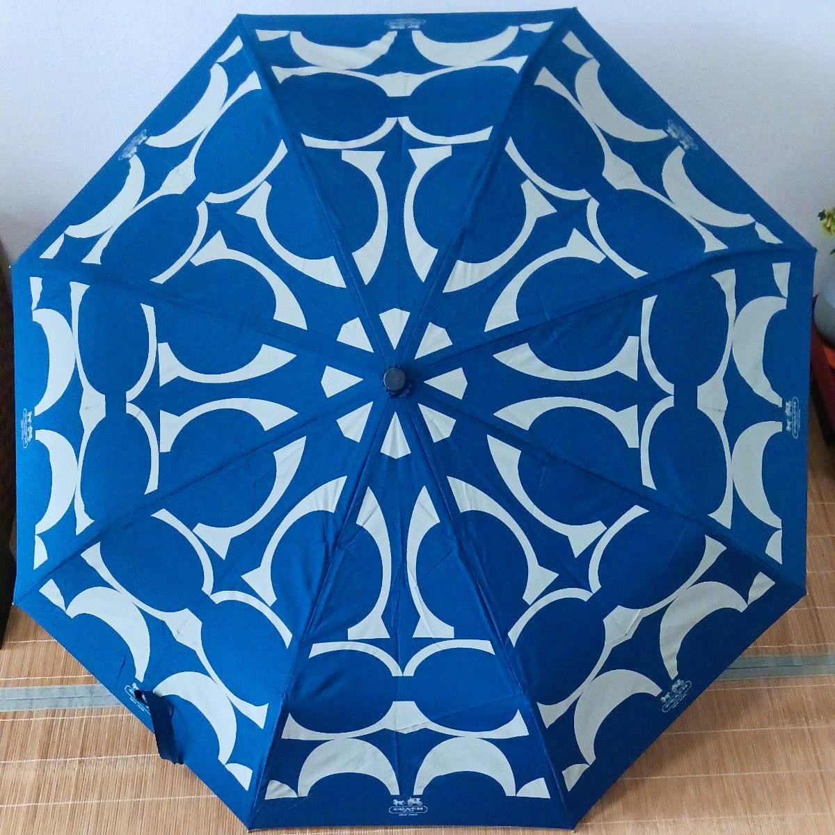 Blue COACH folding umbrella with white signature-pattern canopy shown open.
