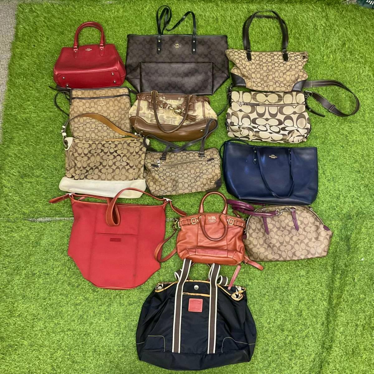 Overhead shot of a set of Coach shoulder and tote bags arranged on green turf, showing various signature monogram and solid-color styles.