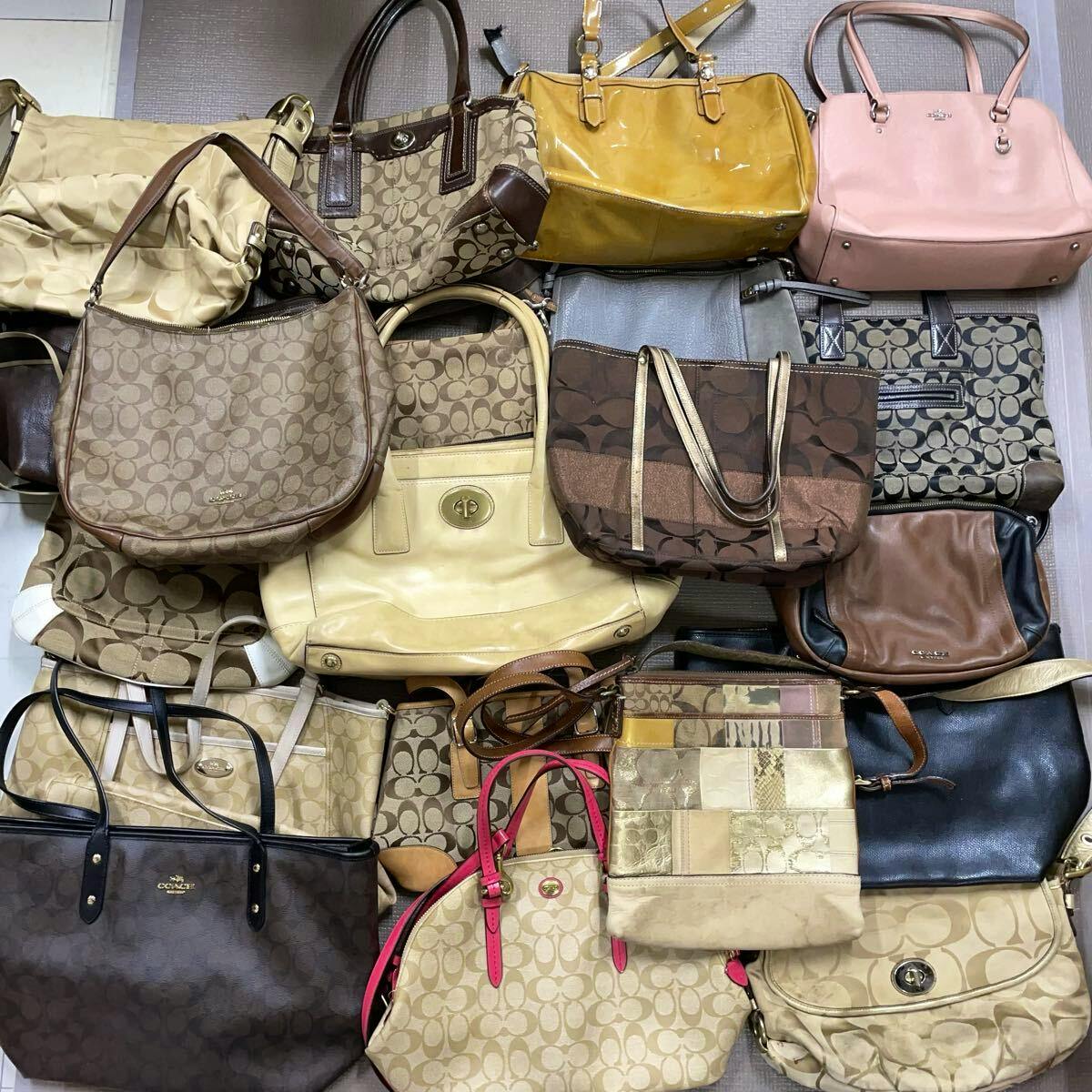 A flat lay of many COACH signature canvas handbags and shoulder bags in various styles.