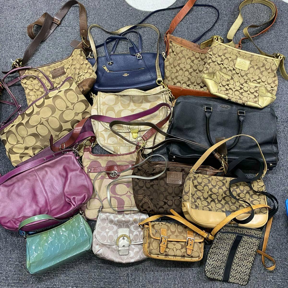 Top-down photo of multiple COACH handbags and shoulder bags on carpet, many showing the signature C canvas pattern.