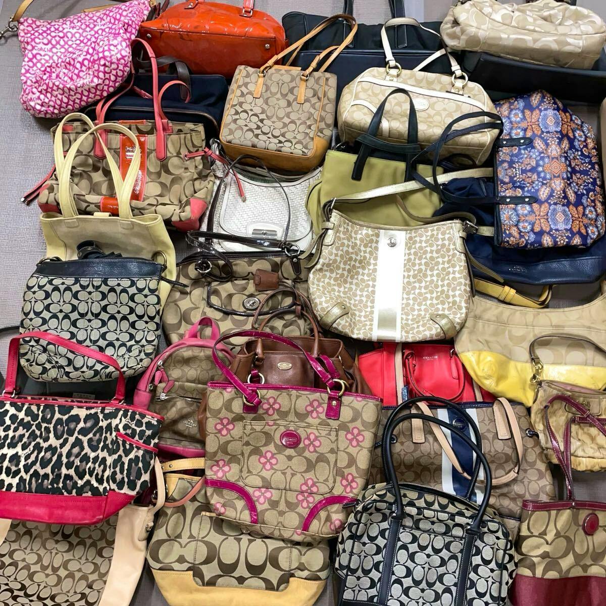 Multiple COACH handbags and pouches in assorted colors and signature canvas patterns laid out together.
