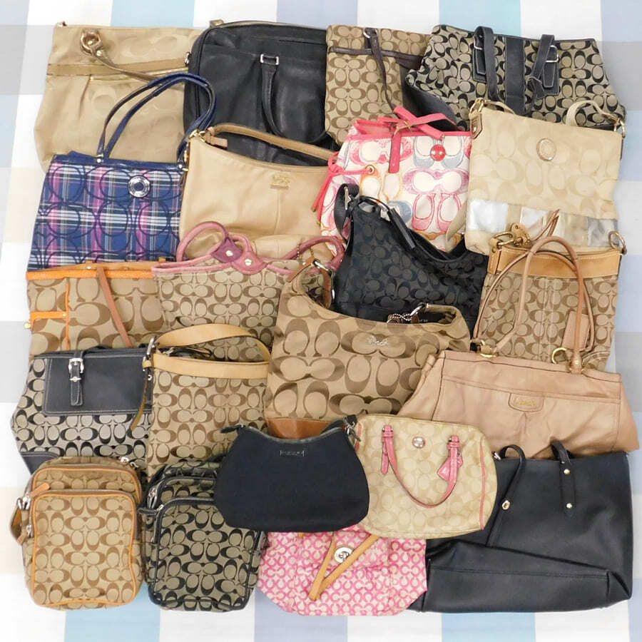 Twenty-two Coach handbags and shoulder/tote bags in various colors and signature patterns laid out together.