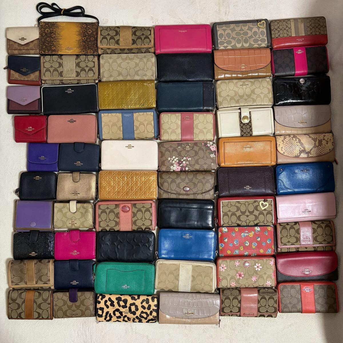 Flat lay of multiple COACH wallets and long wallets in various colors and signature canvas patterns arranged in a grid.