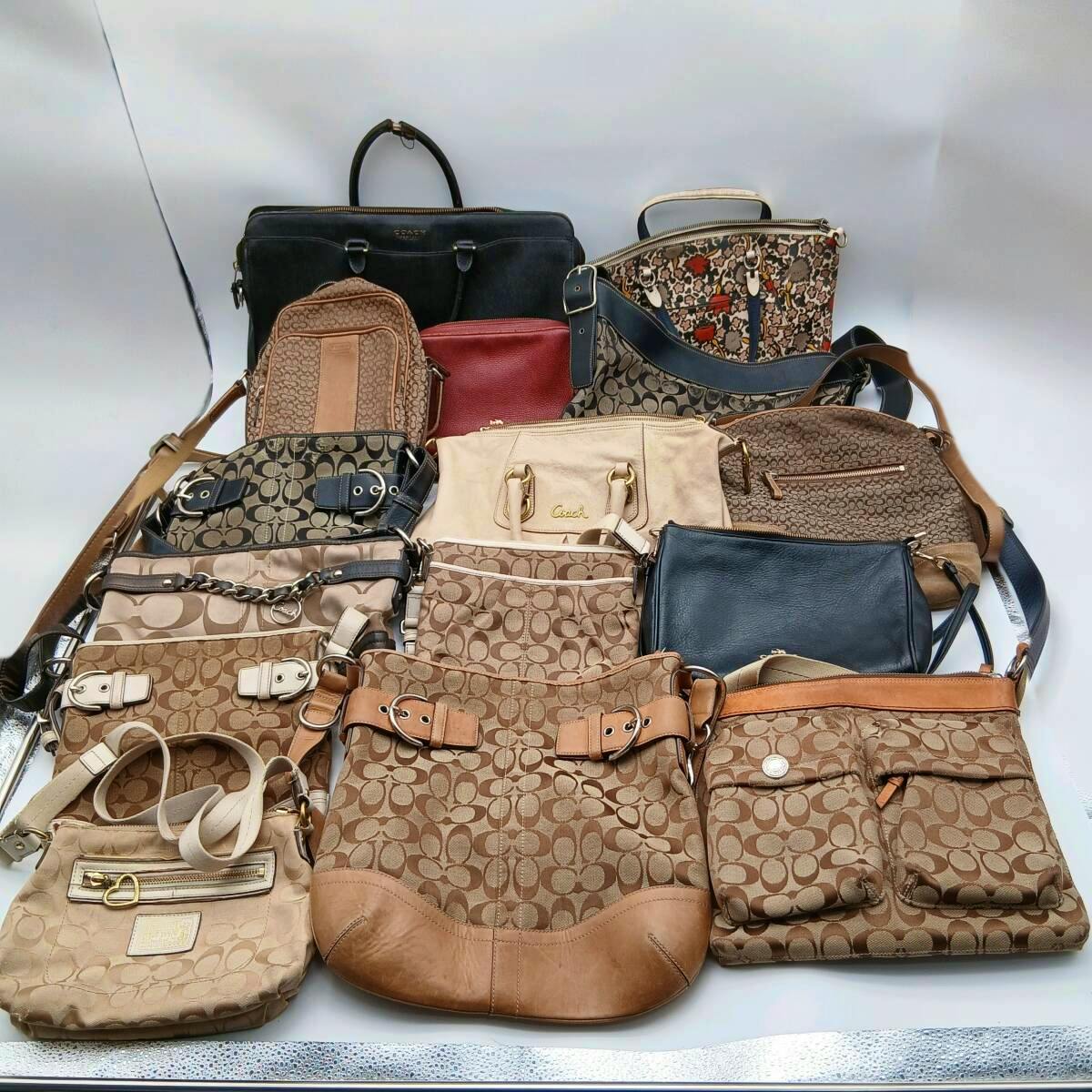 A collection of Coach handbags and shoulder bags in signature C canvas and leather finishes displayed on a white background.