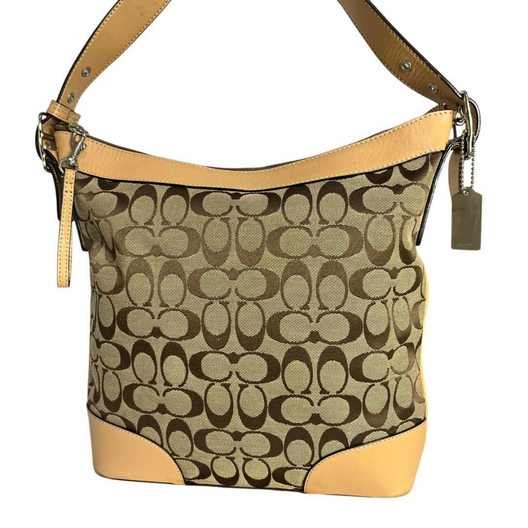 Front view of the brown Coach shoulder bag with signature canvas pattern, tan leather trim, and hanging tag.