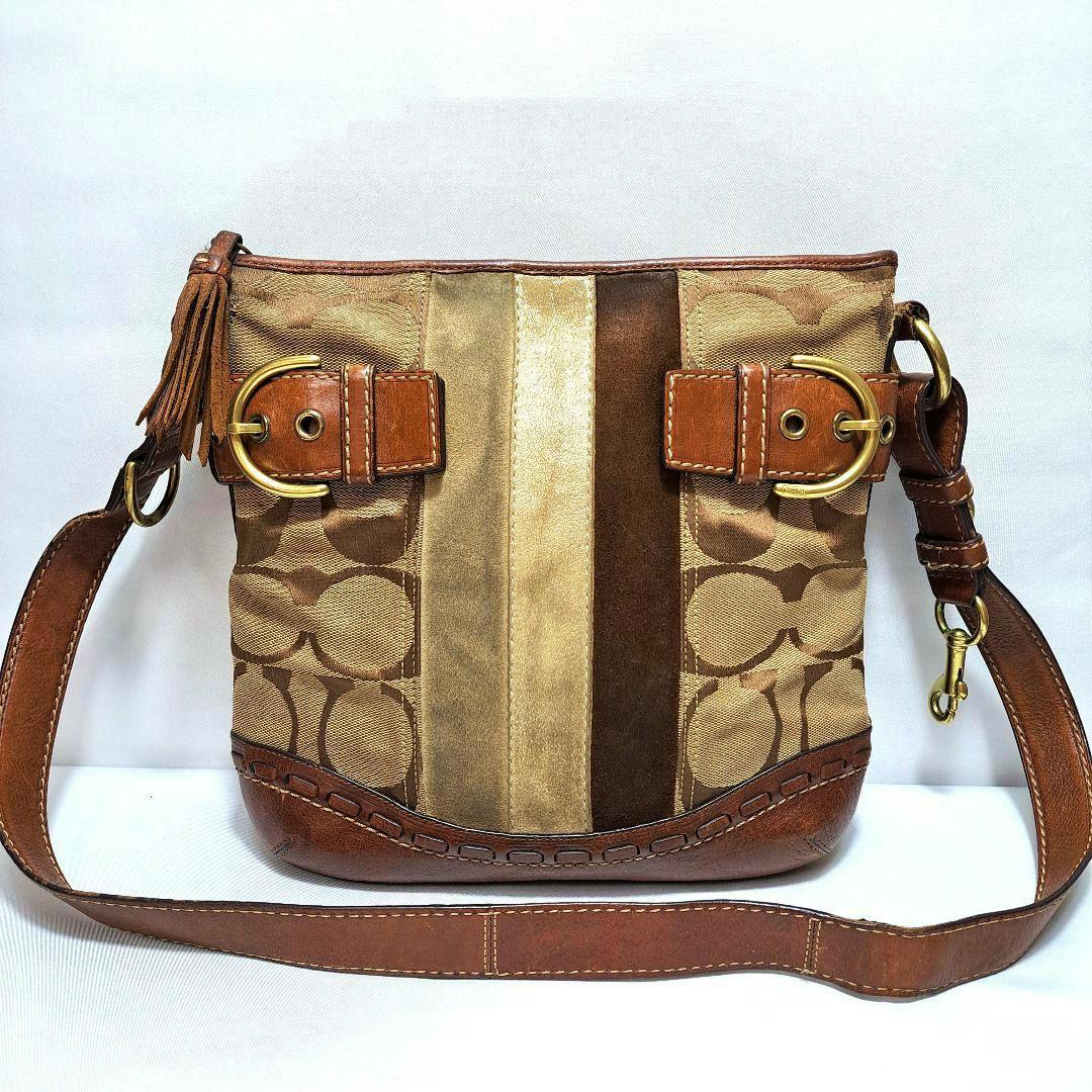 Front view of a COACH signature brown leather shoulder bag with a striped center panel and long strap.