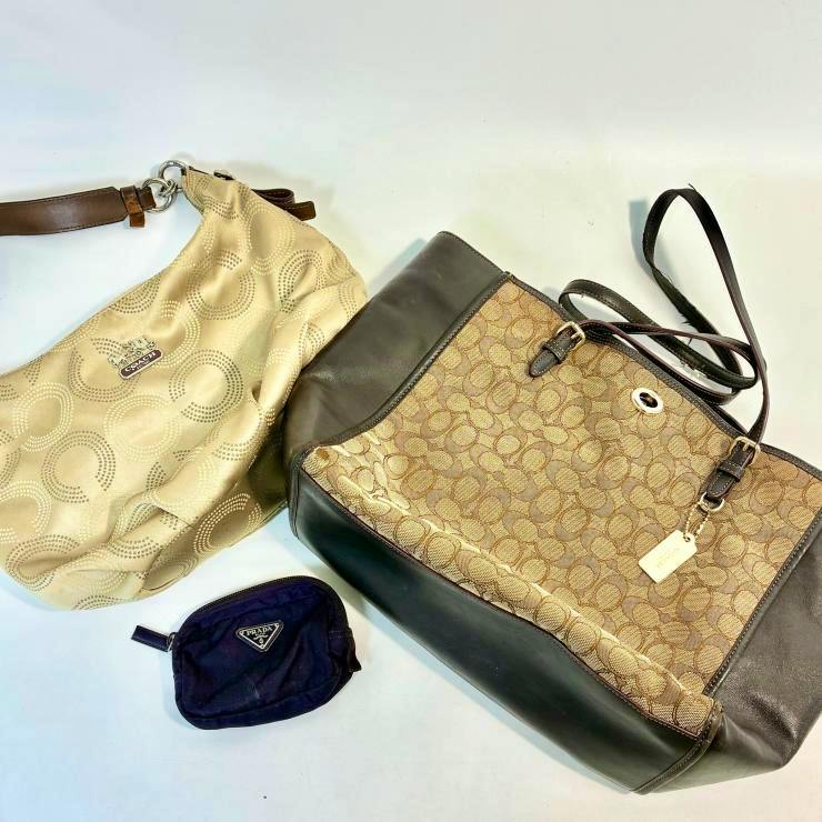 Two Coach bags with signature logo pattern and a small dark pouch displayed on a white background.