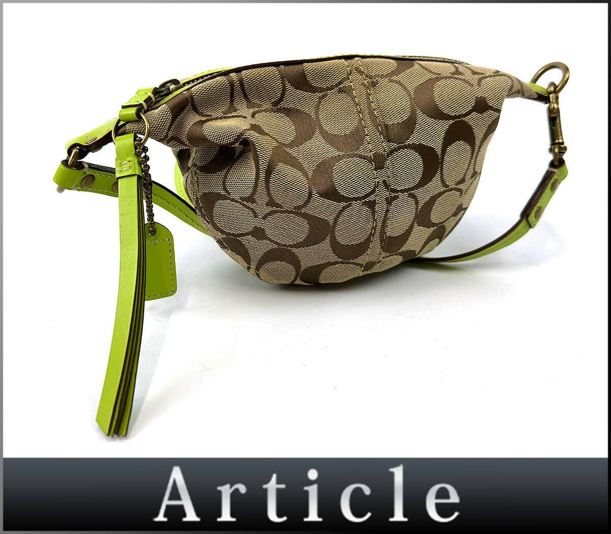 Beige and brown Coach signature canvas mini shoulder bag with a green leather strap and tassel on a white background.