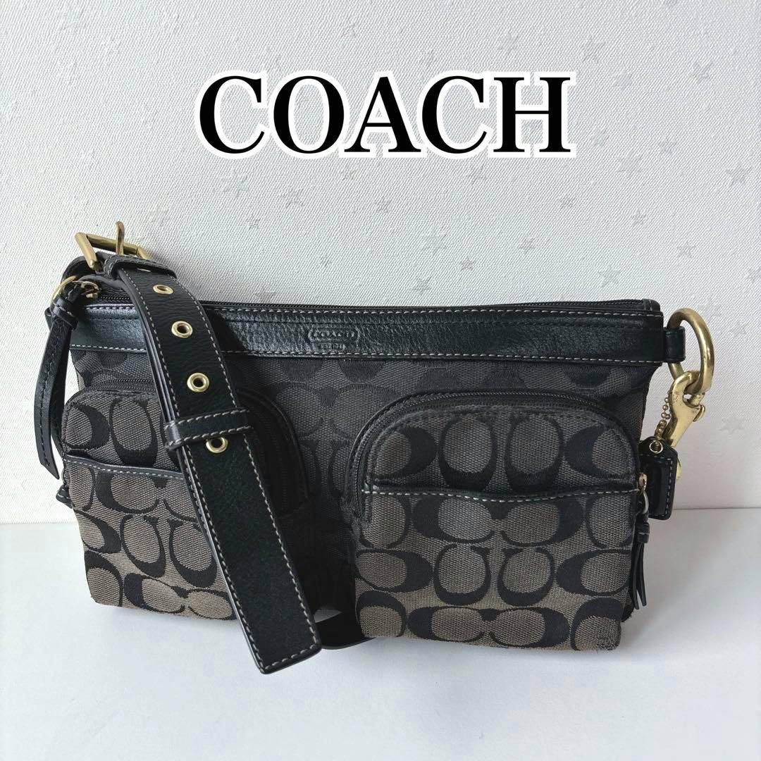 Front view of a black Coach mini one-shoulder canvas bag with signature C pattern, adjustable strap, and two front zip pockets.