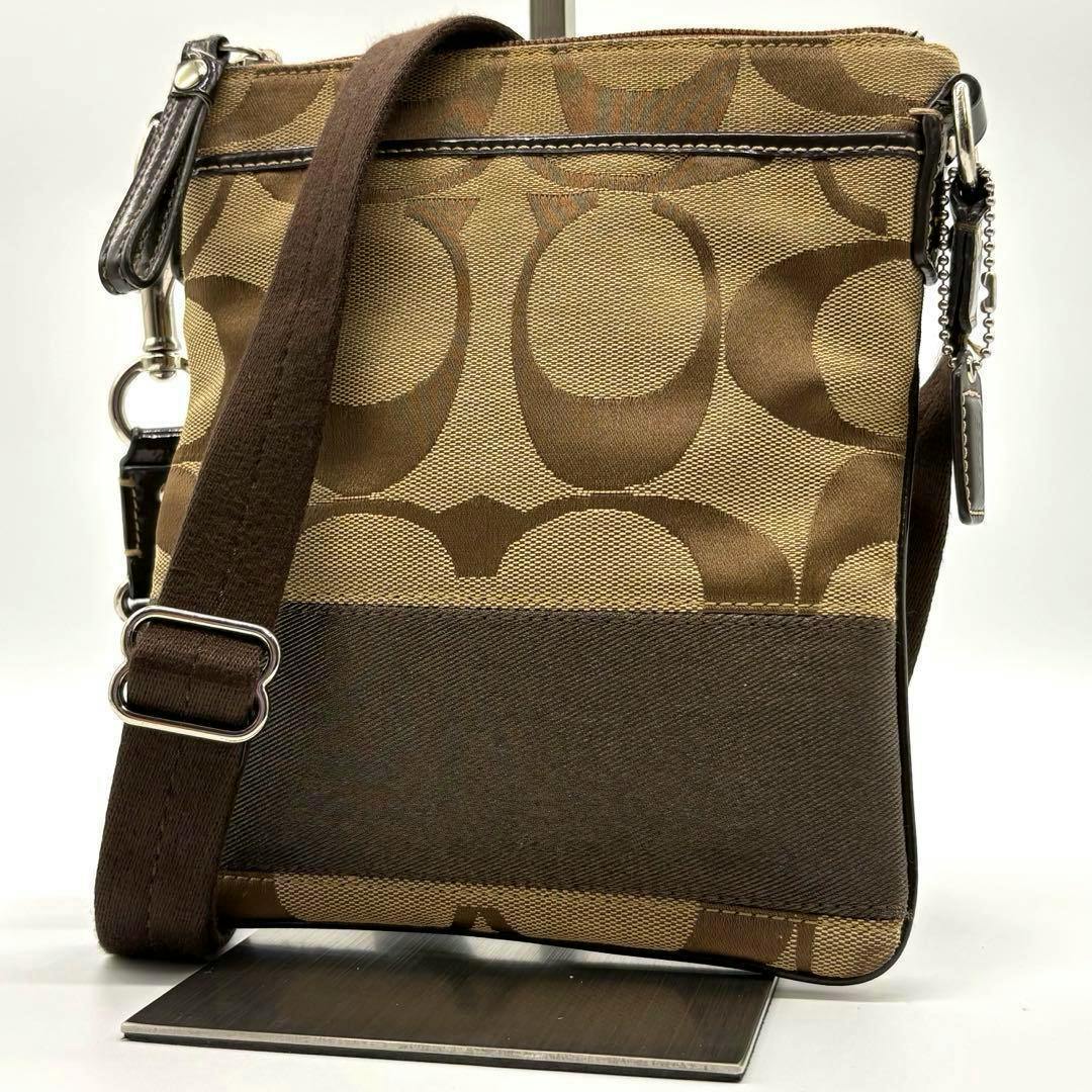 Front view of a brown Coach mini shoulder bag in signature canvas with a brown strap and metal hardware.