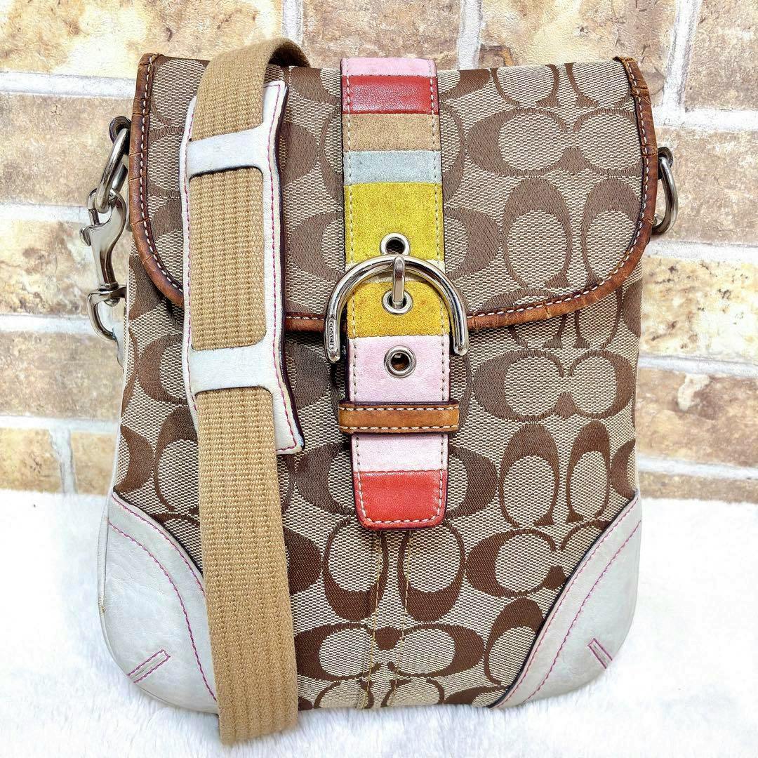 Front view of a Coach signature canvas shoulder bag with a multicolor buckle detail and a beige crossbody strap.