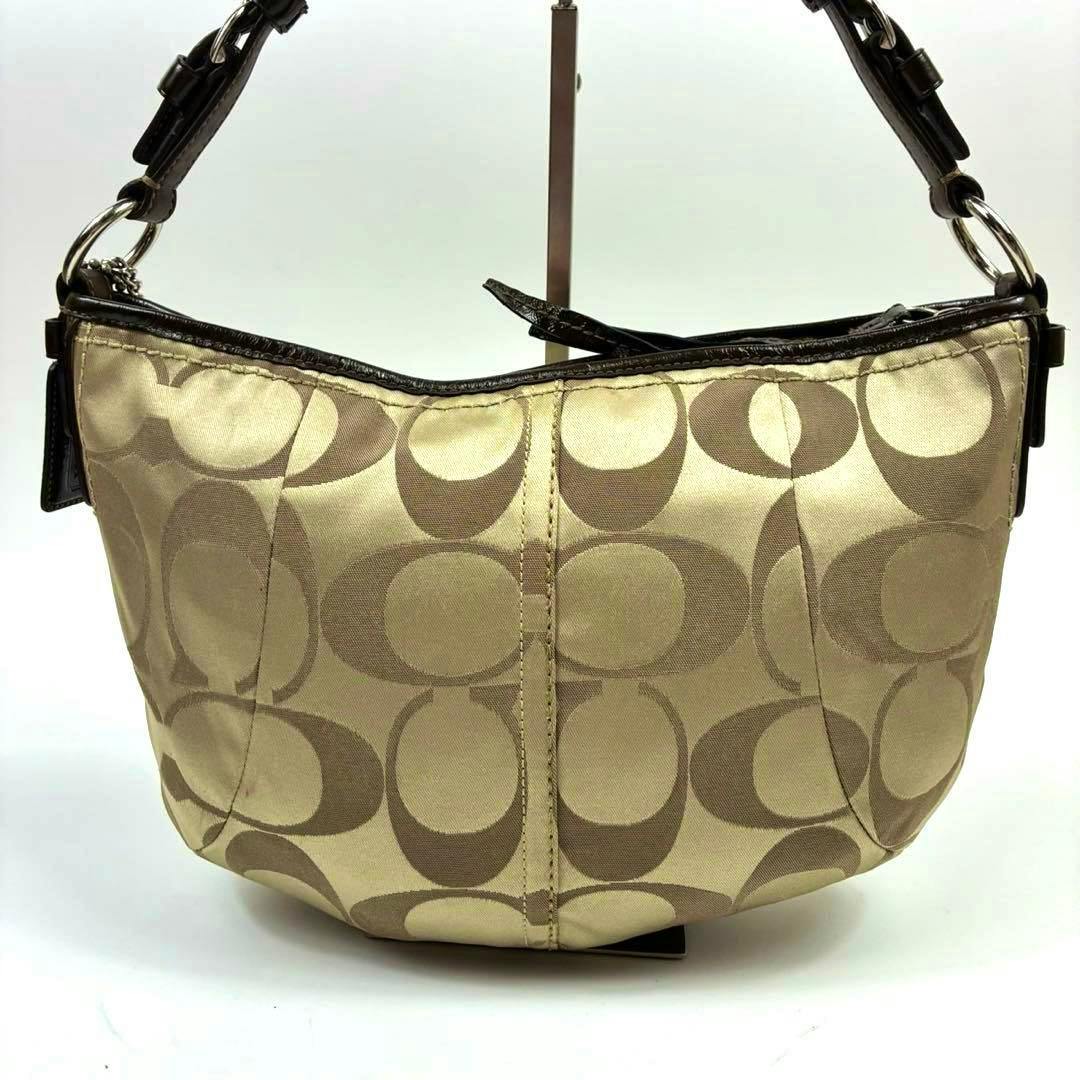 Front view of a beige Coach signature canvas one-shoulder bag with brown leather trim and a short shoulder strap.