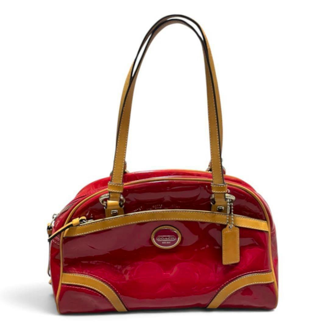 COACH signature enamel mini boston bag in pink patent leather with tan leather handles and trim on a white background.