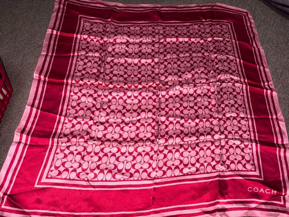Pink COACH signature-pattern polyester scarf laid flat showing the repeated 'C' motif and border.