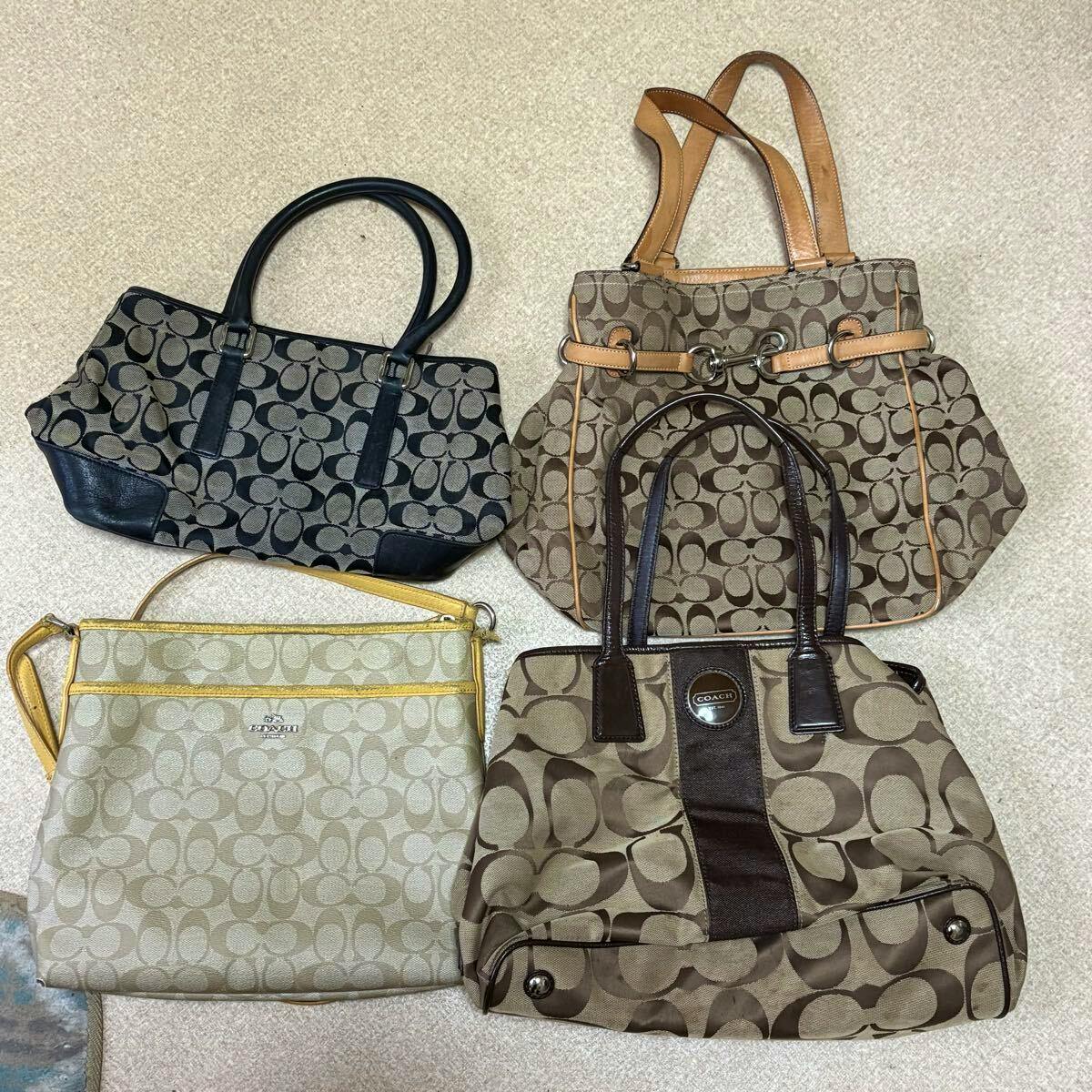 Four Coach signature-print bags arranged on a light carpeted floor.