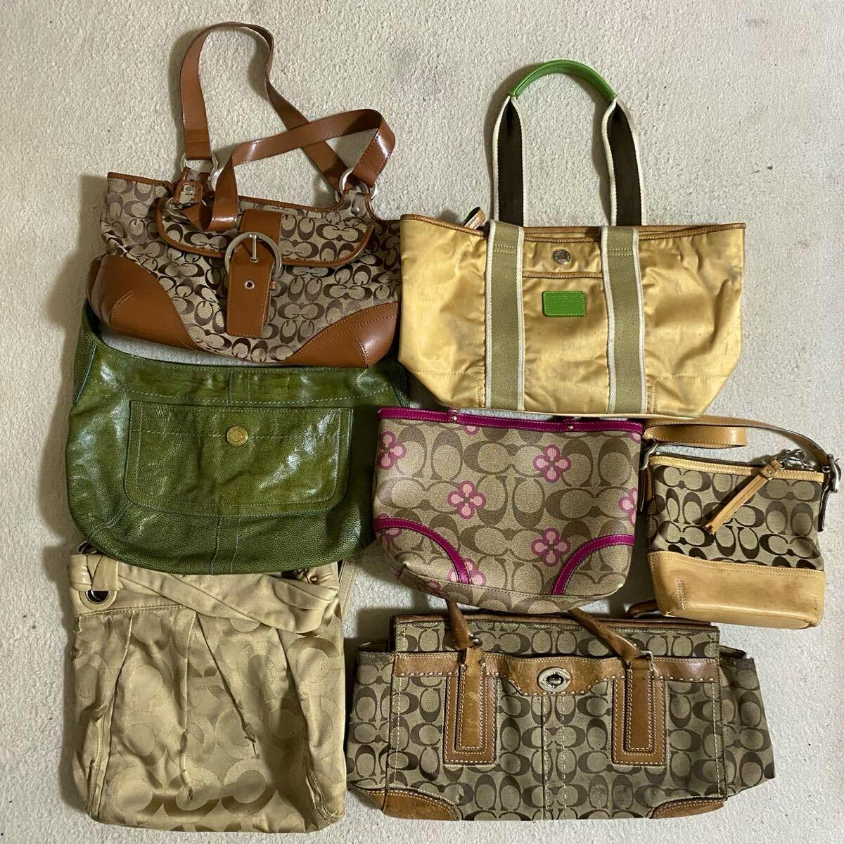 Flat lay of seven COACH bags featuring signature monogram canvas and mixed leather details.