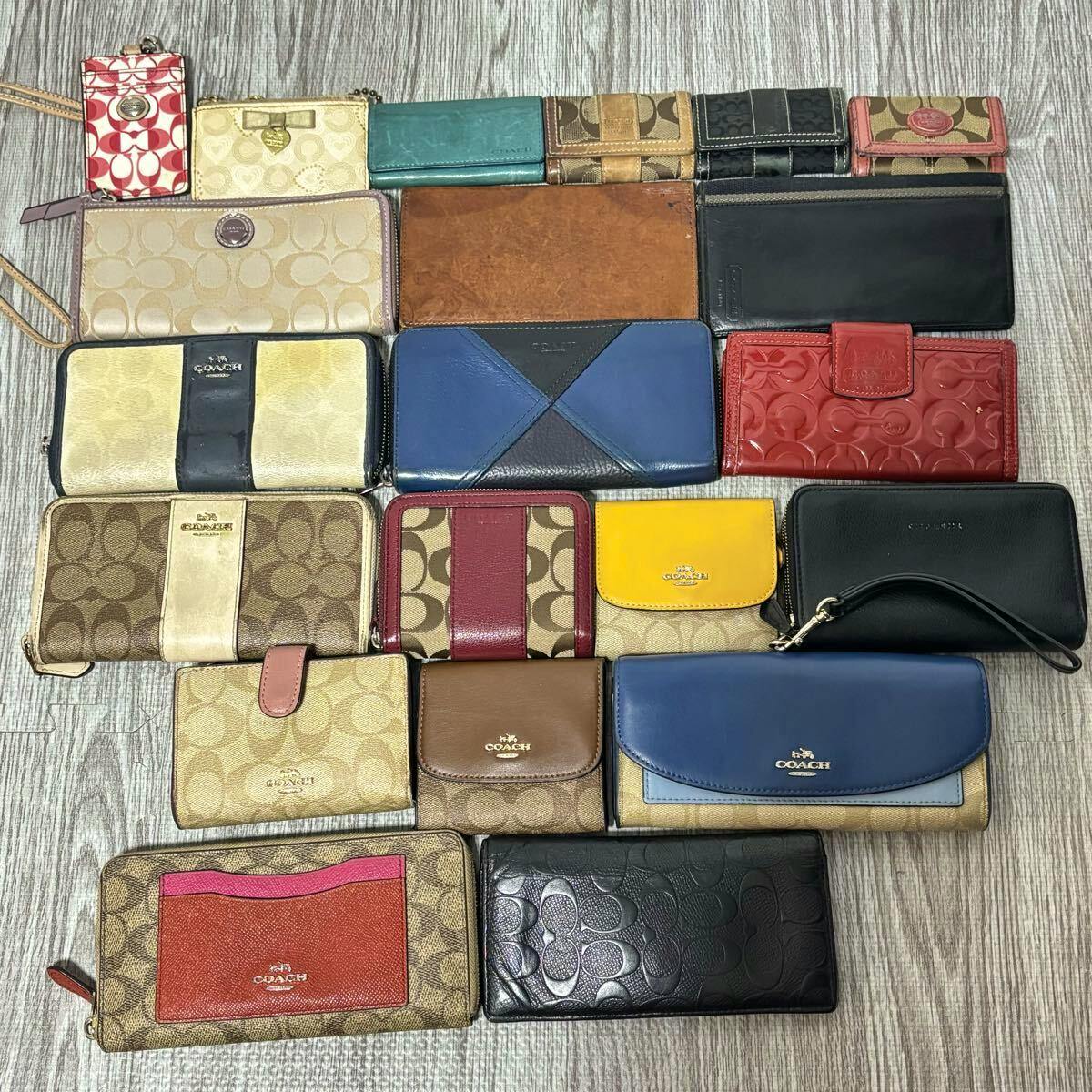 Flat lay of multiple Coach wallets, card cases, and small accessories arranged on a wood-textured floor.