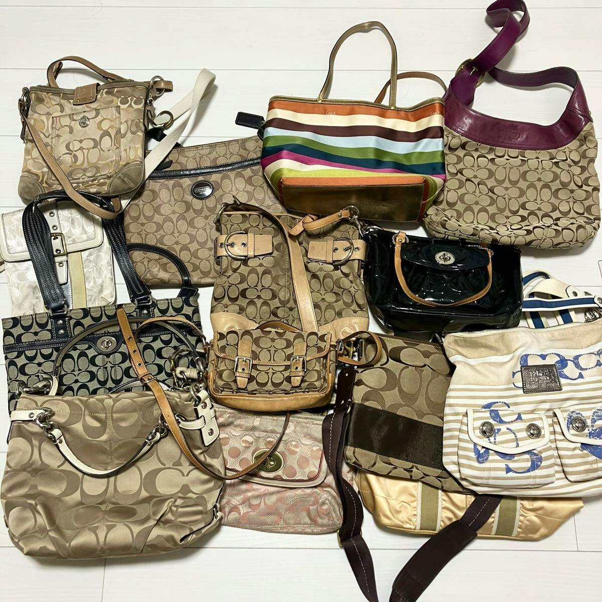 Multiple COACH signature shoulder bags and handbags arranged on a floor, showing various colors and patterns.