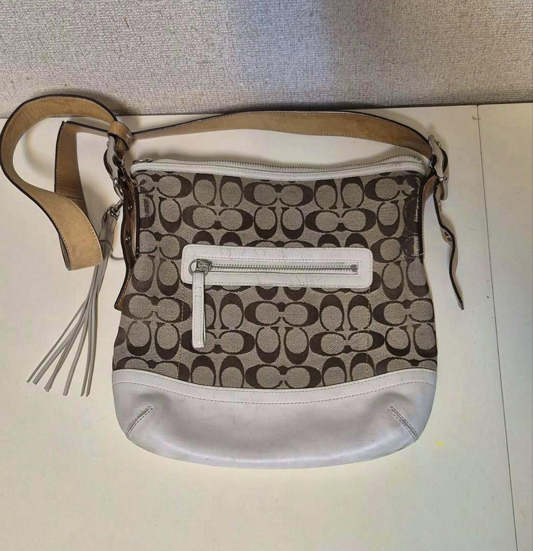 Brown and white Coach signature canvas shoulder bag with front zip pocket, leather trim, and adjustable strap.
