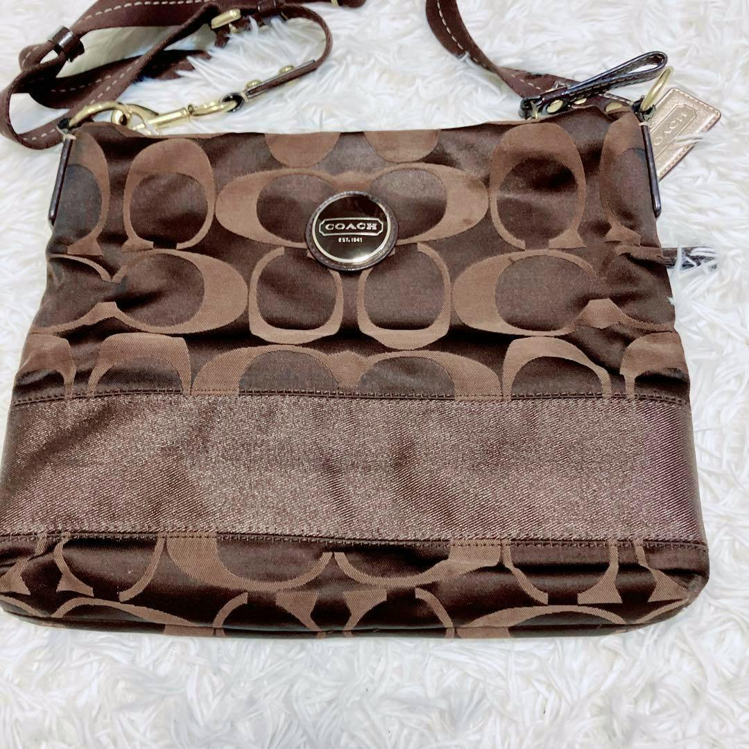 Brown Coach signature canvas shoulder bag laid flat on a white fuzzy background.