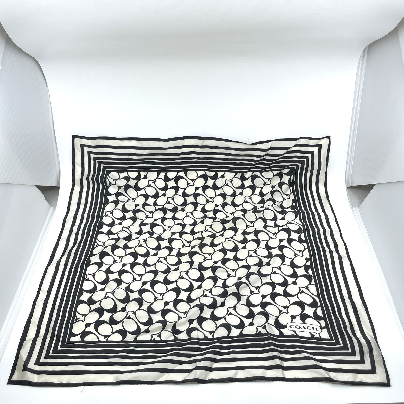 Monochrome Coach silk scarf with signature pattern laid flat on a white background.