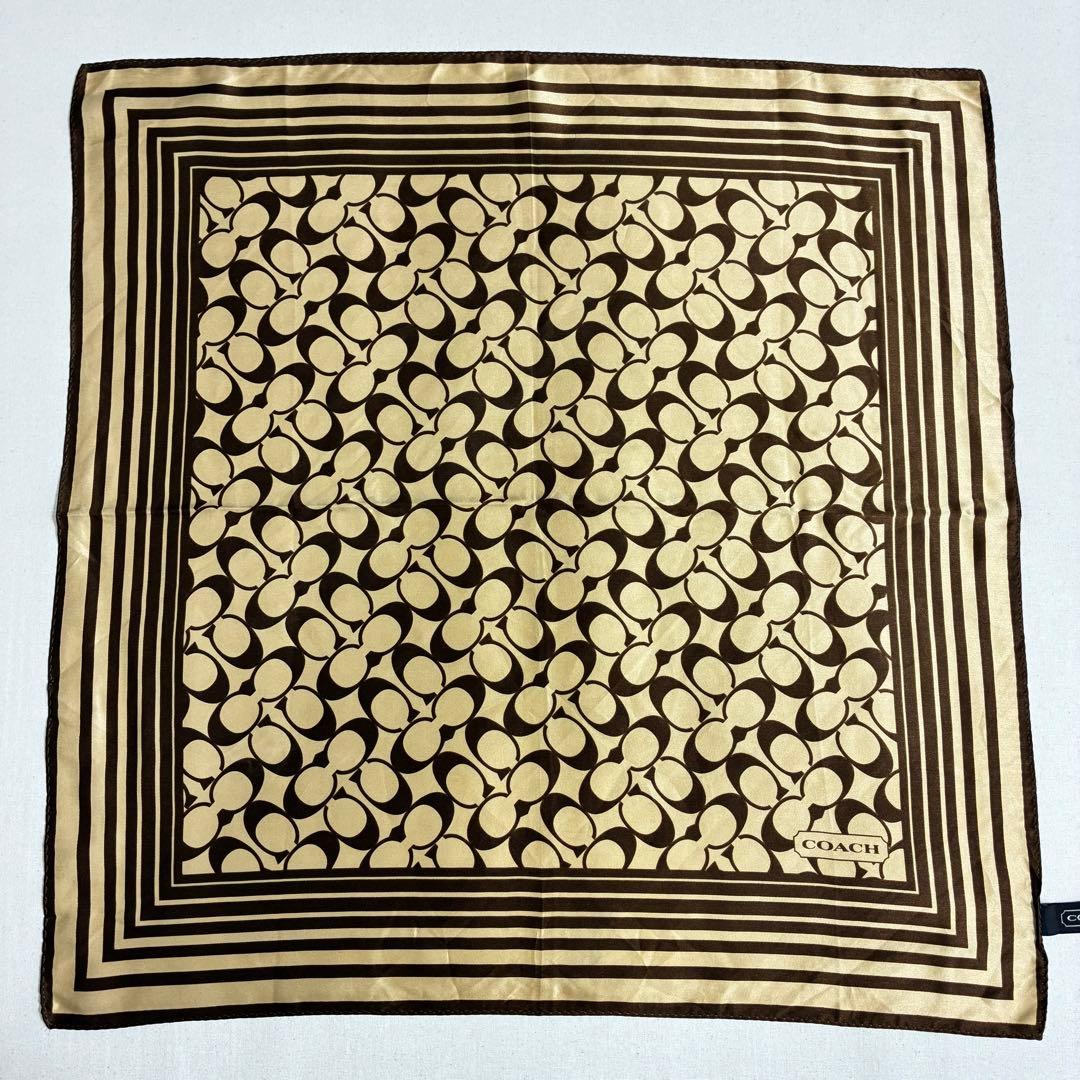 Brown and beige silk scarf with Coach signature "C" motif and concentric square border laid flat.