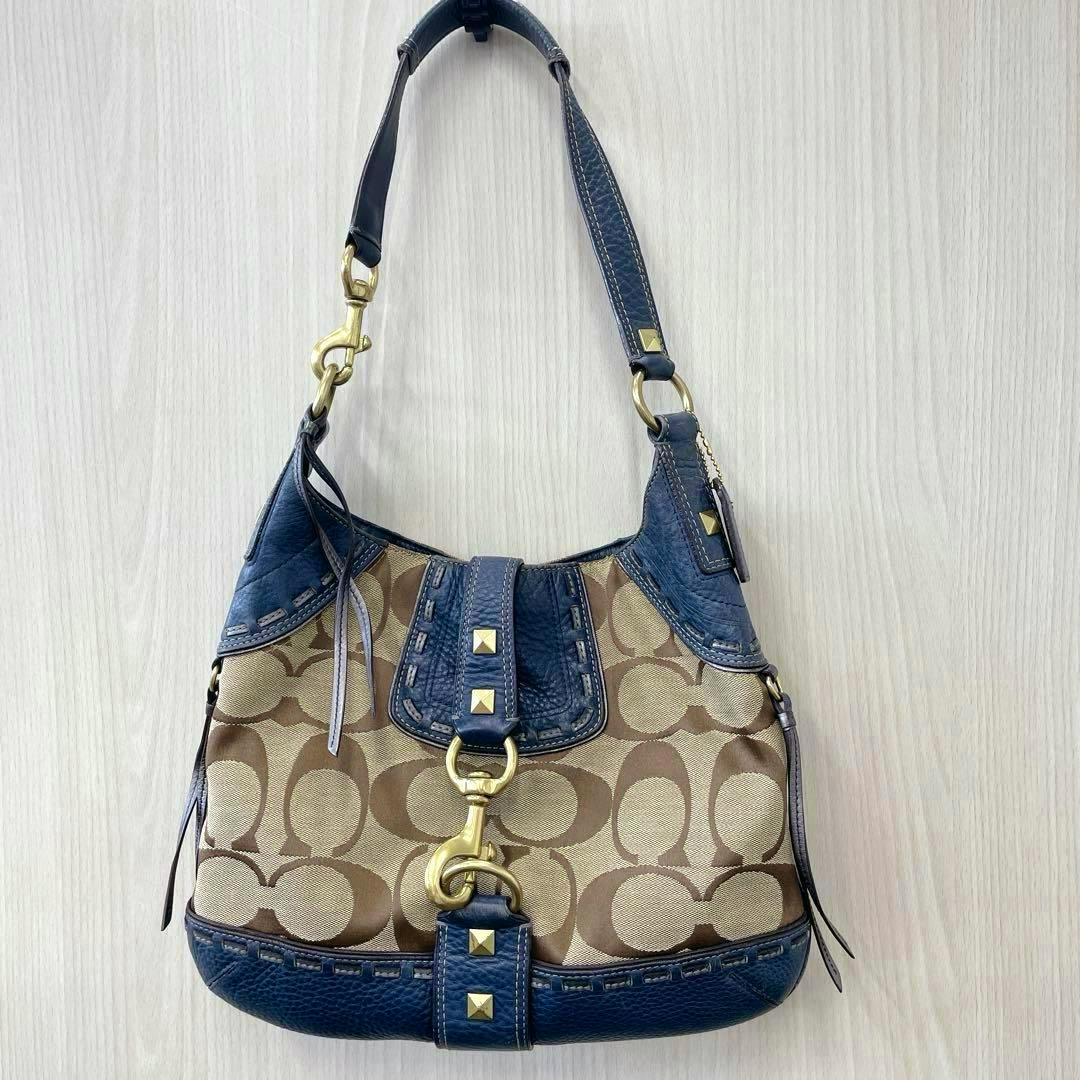A navy-trim Coach signature canvas shoulder bag with beige C pattern, gold clasp and stud details.