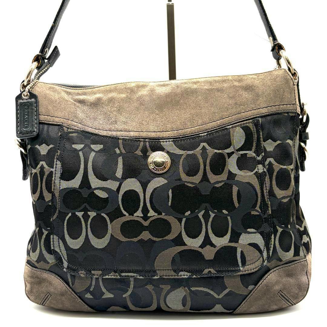 Front view of a COACH signature canvas one-shoulder bag showing the logo pattern, suede trim, and a shoulder strap.