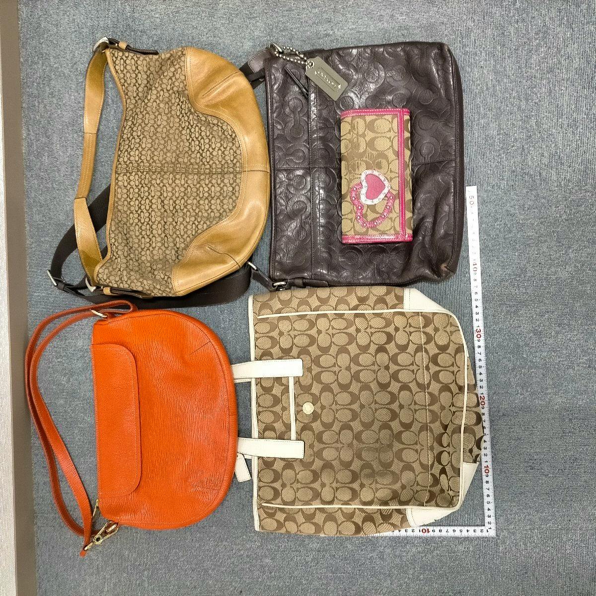 Five Coach bags and a small Coach wallet with signature C pattern and different colors arranged flat on a gray surface with a measuring tape at the edges.