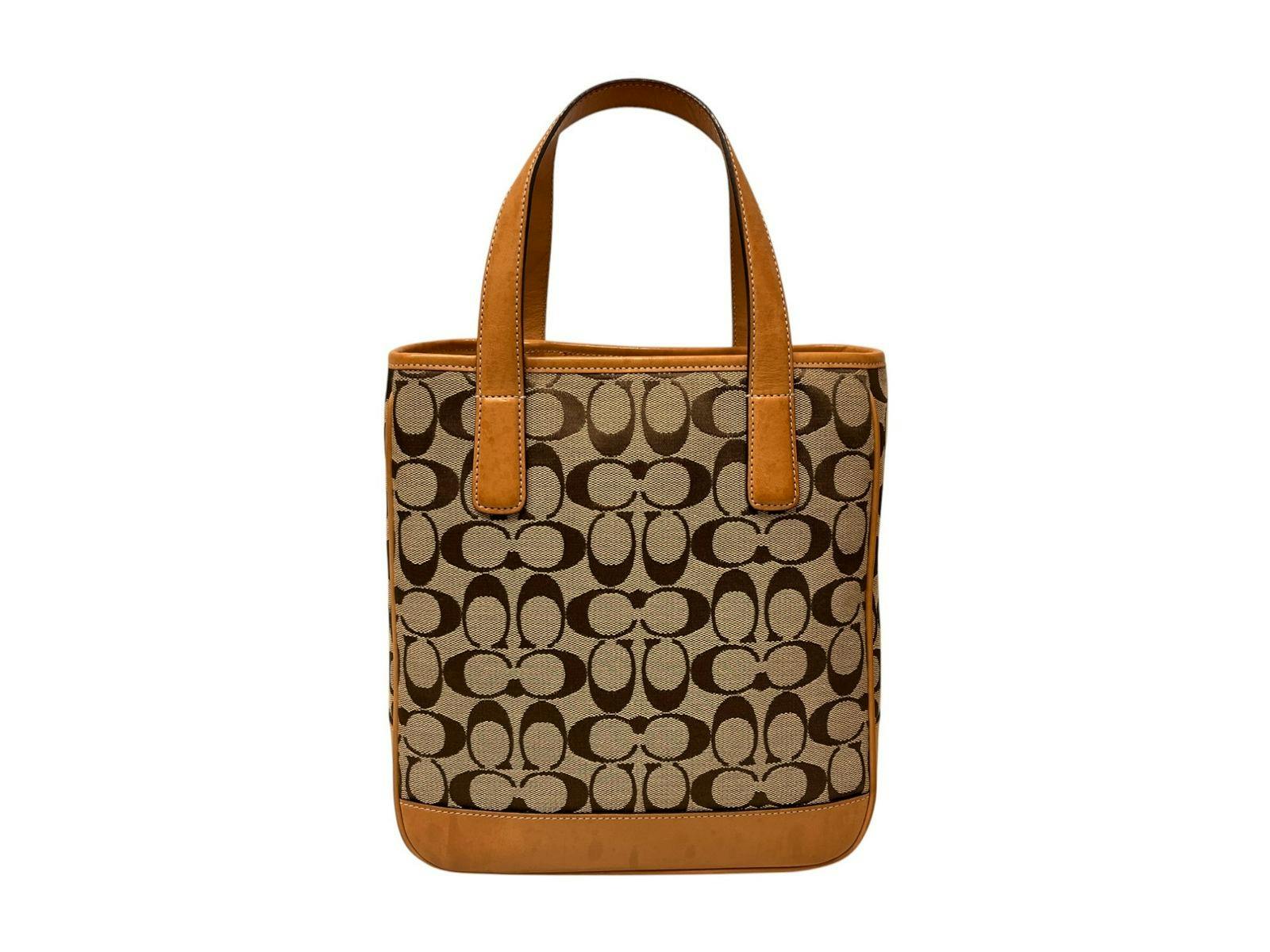 Front view of a beige COACH signature-pattern canvas tote bag with brown leather trim and handles.
