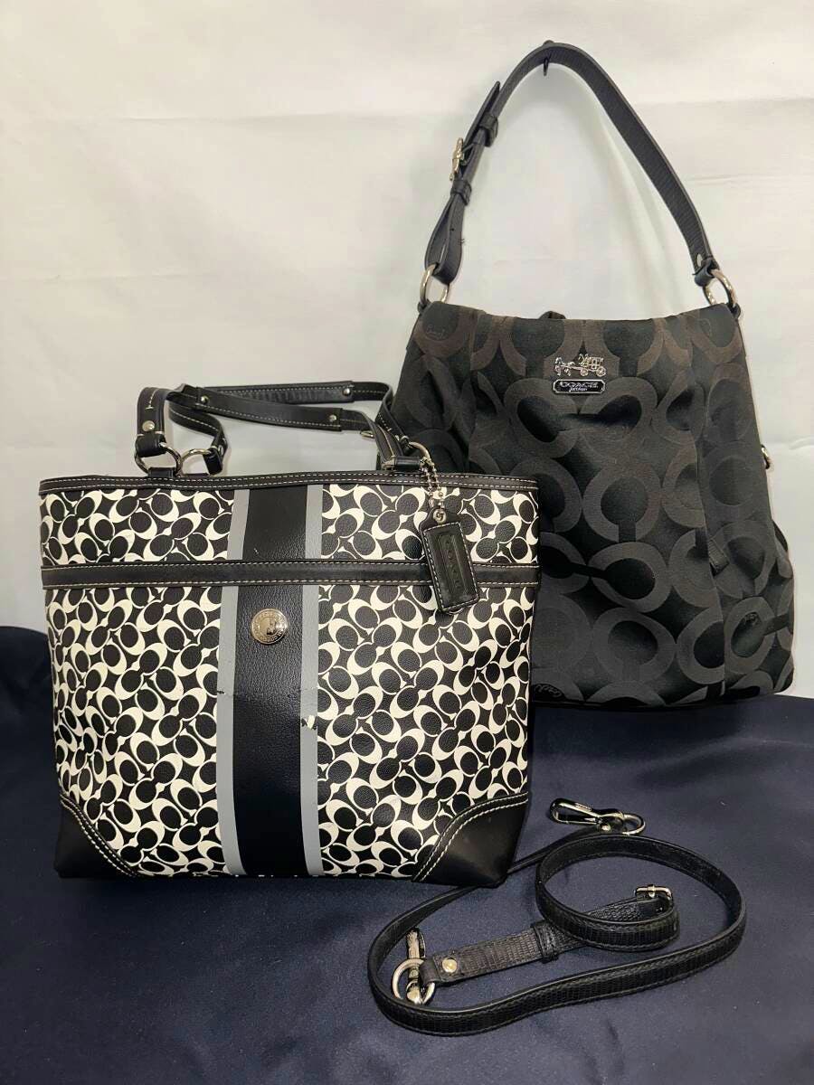 Two COACH signature bags: a black one-shoulder bag and a black-and-white signature tote with a separate shoulder strap, displayed on a dark surface.