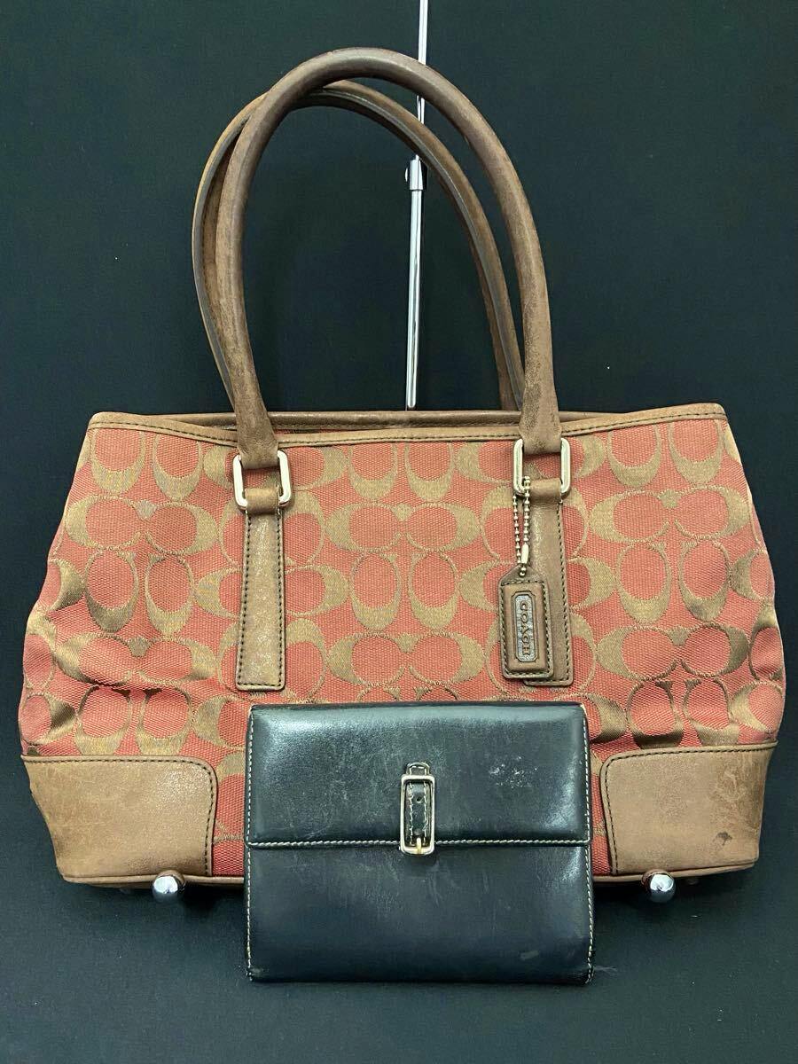 Front view of a Coach signature canvas tote bag with leather trim and a black wallet placed in front.