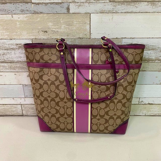Front view of the COACH signature beige canvas tote bag with purple leather trim, a central purple-and-white vertical stripe, and double shoulder straps.